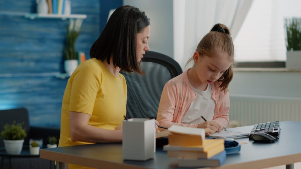 Pupil and Tutor doing homework together with books
