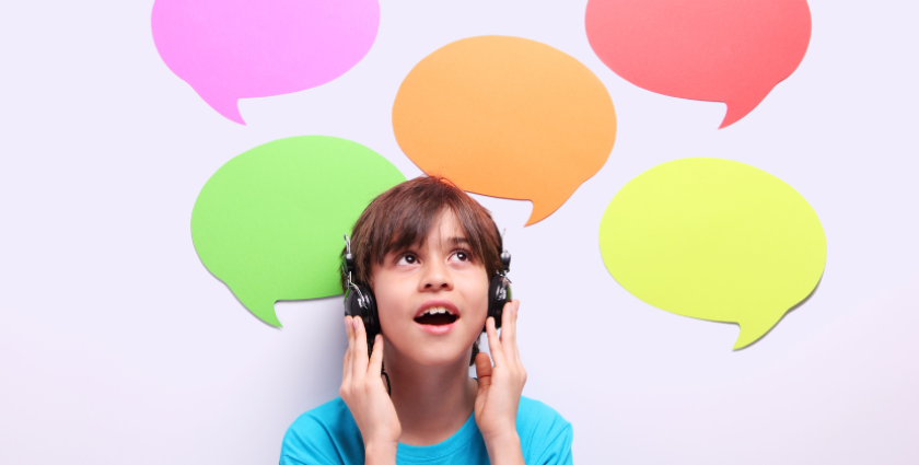 A child wearing headphones looks upwards with an excited expression, embodying the spirit of auditory learners. Colorful speech bubbles in pink, orange, green, yellow, and red float above their head against a light background.
