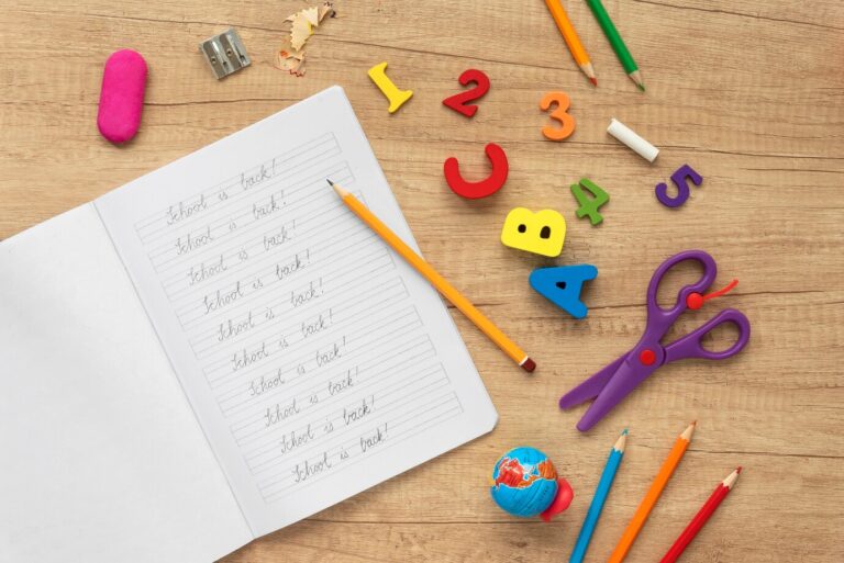 A collection of school supplies including a notebook, pencil, and scissors displayed on a flat surface.