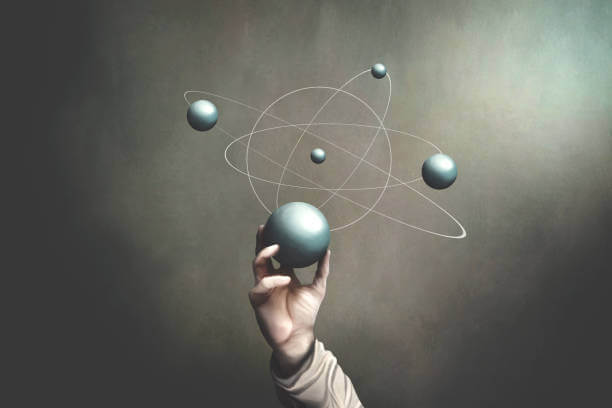 A person raises a ball featuring an atom symbol, symbolizing the principles of physics and scientific exploration.