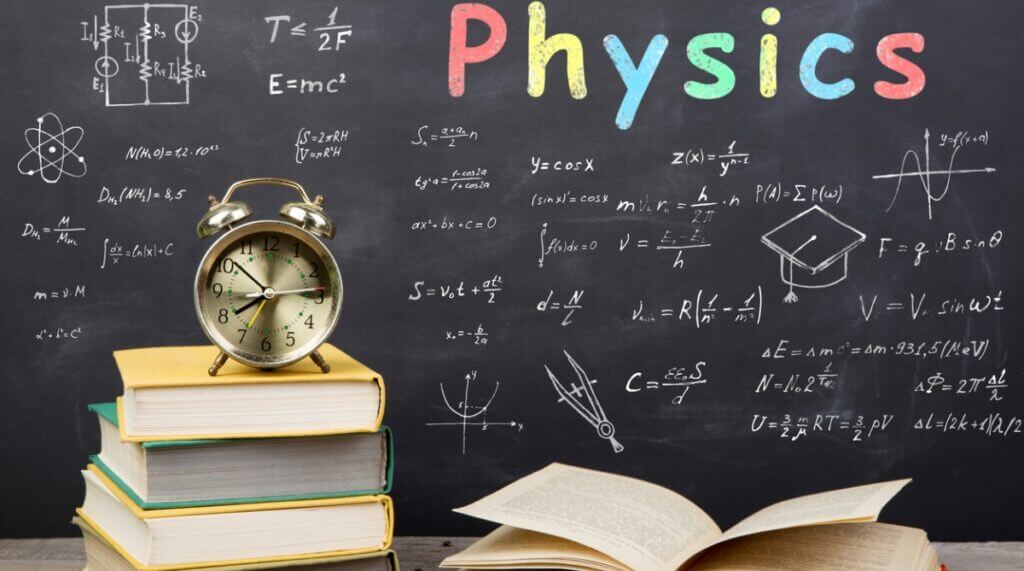 A blackboard filled with physics equations, accompanied by a clock and stacked books, illustrating a study environment.