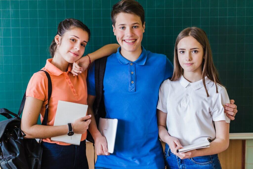 Three secondary school students collaborate at a desk, focused on their studies.