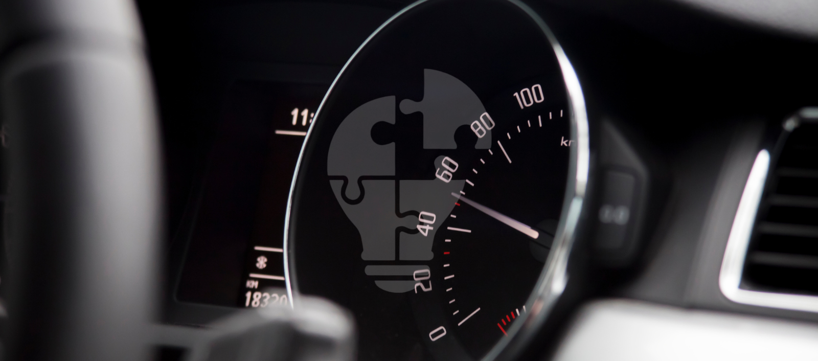 Close-up of a car speedometer with a puzzle piece and lightbulb graphic overlay, indicating innovation in automotive design.