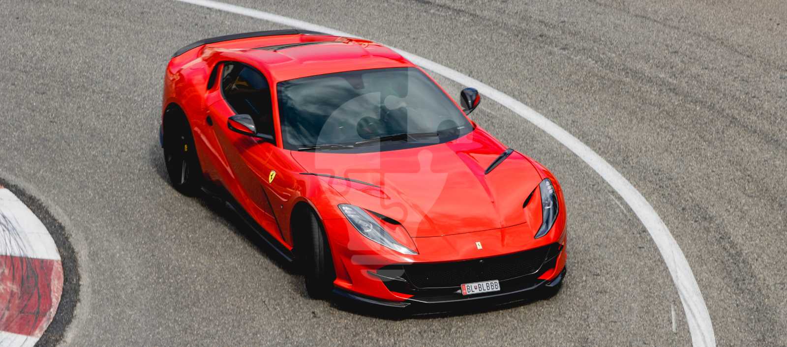 A sleek red Ferrari 812 Superfast accelerates on a racetrack, showcasing its aerodynamic design and sporty features.