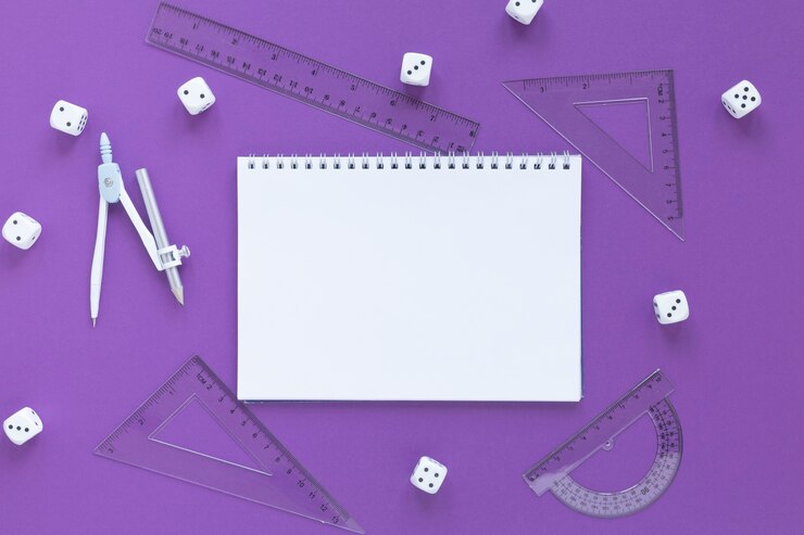 A blank spiral notepad surrounded by dice and transparent geometry tools on a purple background.