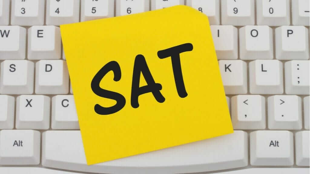 A yellow sticky note with "SAT" written in bold black letters placed on a white computer keyboard.