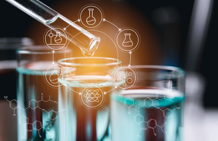 A dropper releasing liquid into a test tube with chemical symbols and lab equipment icons in a blurred background.
