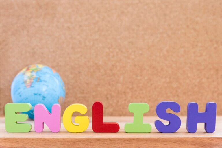 Colorful wooden letters spelling "ENGLISH" with a globe in the background, set against a corkboard surface.