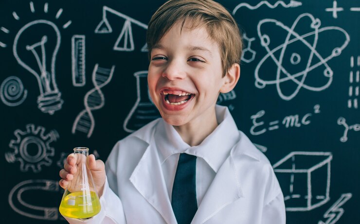 A young scientist in a lab coat holds a flask of yellow liquid, with a blackboard covered in scientific drawings and formulas behind him.