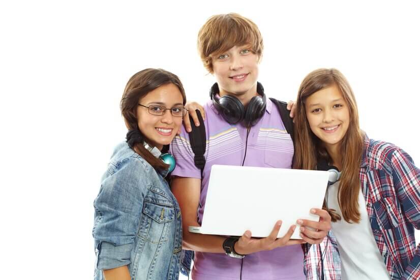 A diverse group of individuals, including men and women, are gathered together smiling while holding a piece of paper. One person is wearing a scarf, and others are dressed in casual clothing such as shirts. The atmosphere appears cheerful and collaborative.