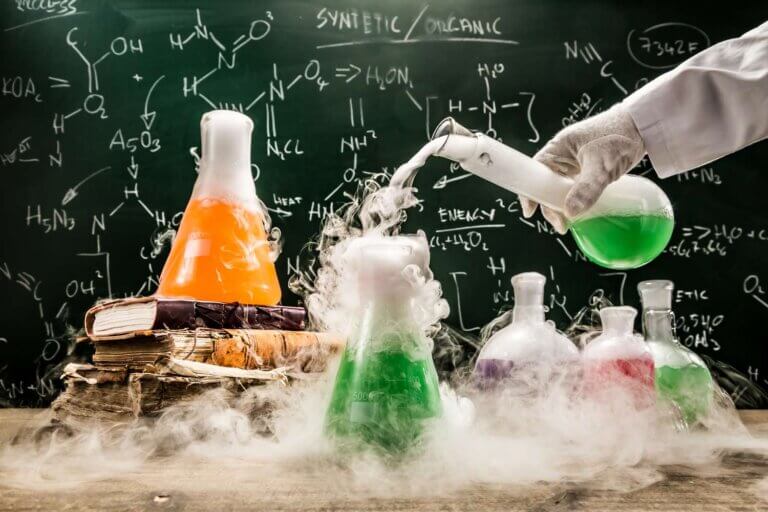 A scientist in a lab coat pours green liquid into a flask, surrounded by colorful flasks and swirling steam, with chemical equations in the background.