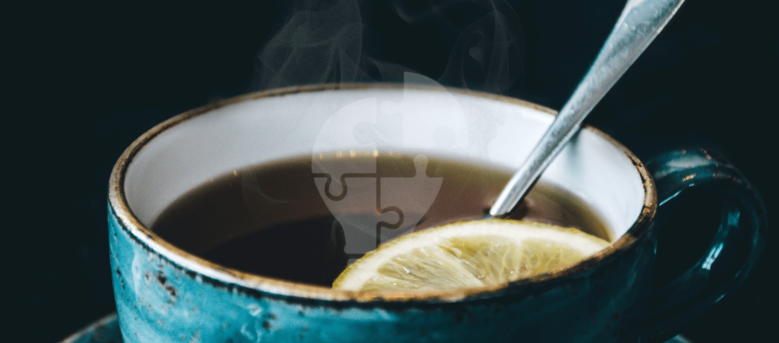 A steaming cup of tea with a slice of lemon and a spoon, set against a dark background, exudes warmth and comfort.