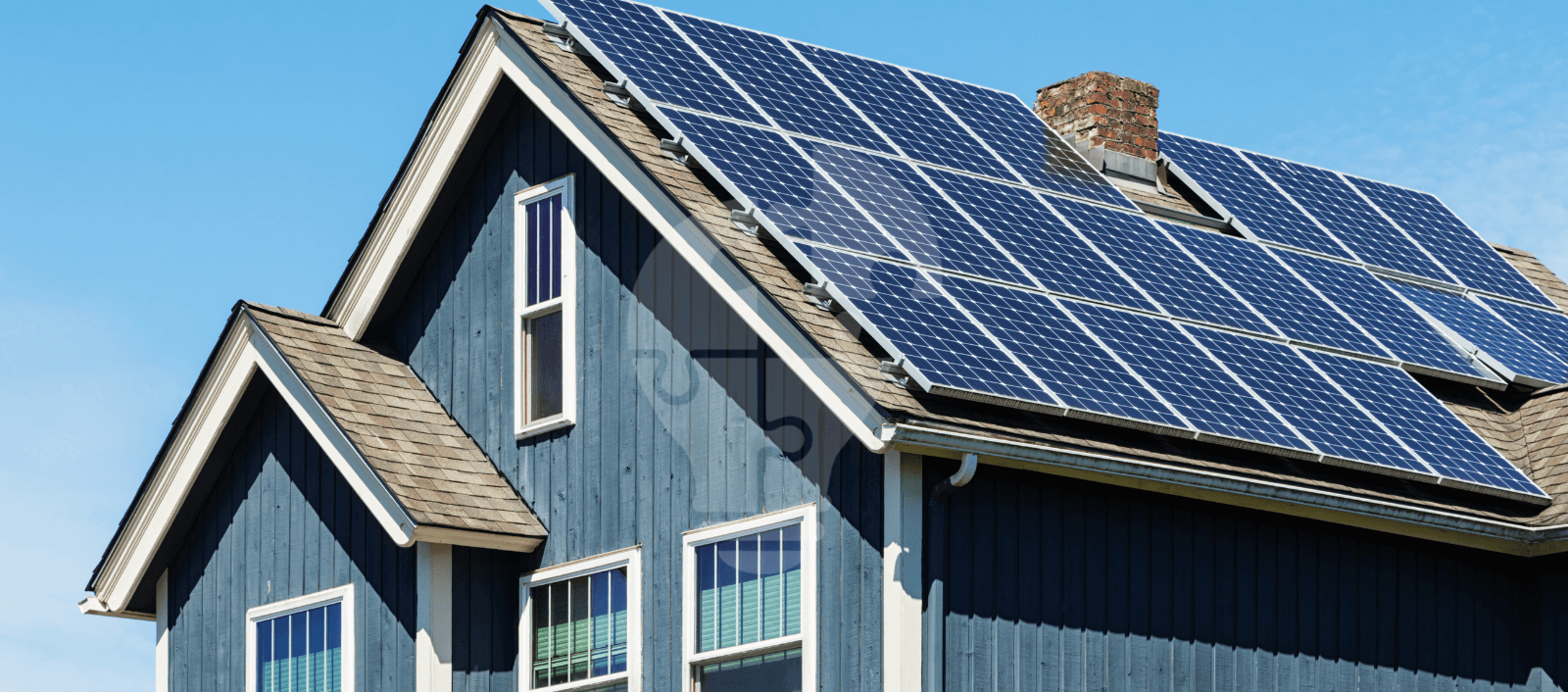 A blue house roof with several solar panels under a bright blue sky, showcasing renewable energy usage.